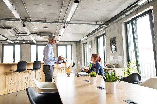 Two business people in creative office discussing a project together.