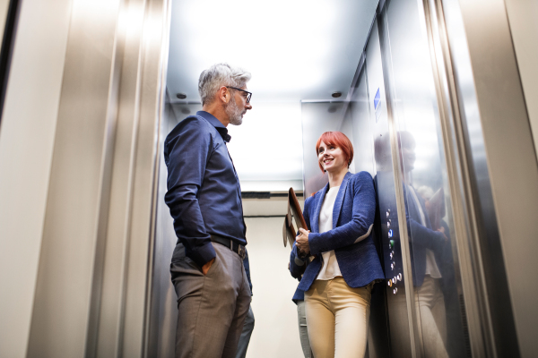 Two business people in the elevator in modern office building.