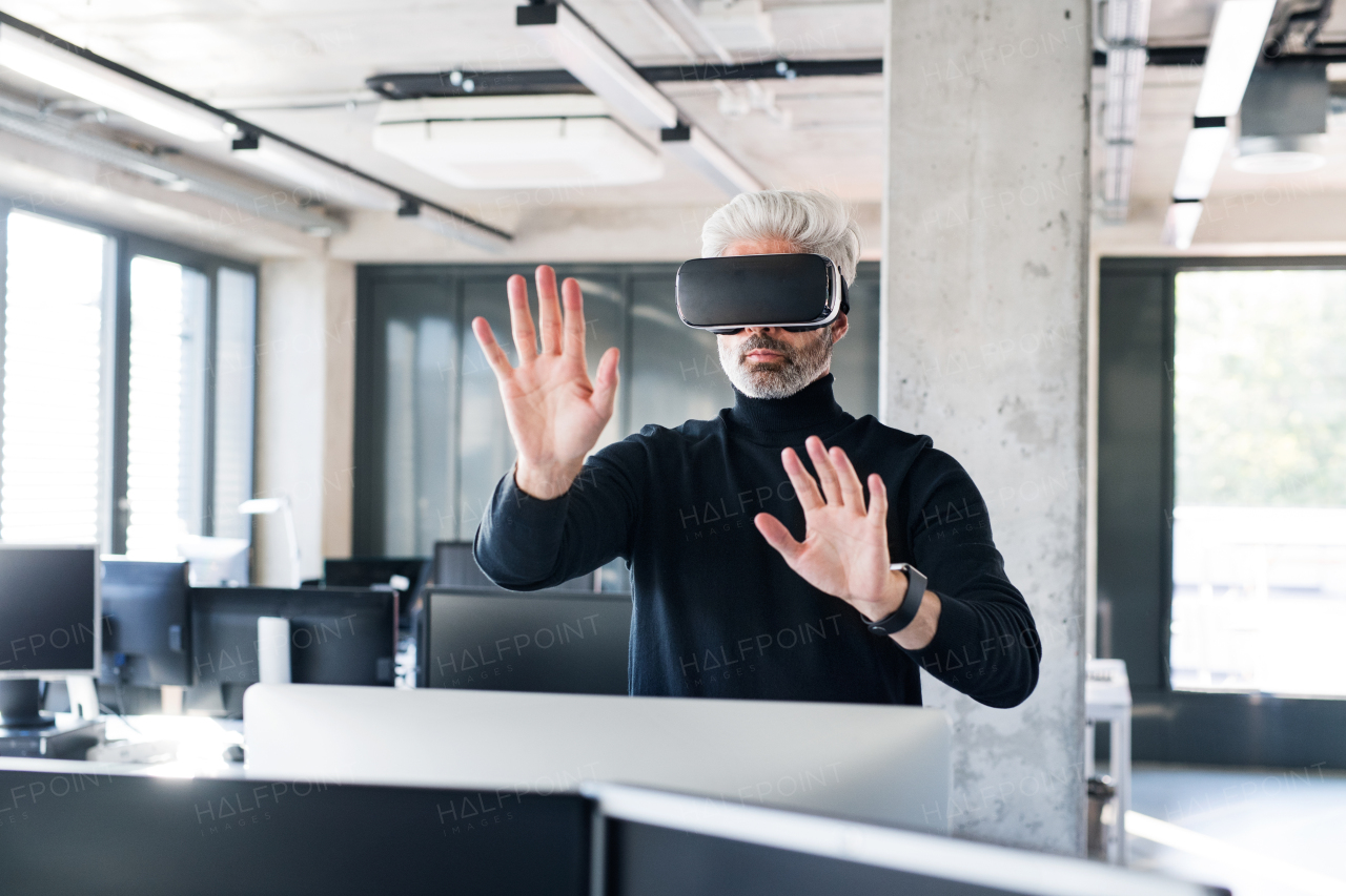 Handsome mature businessman with virtual reality goggles in the office.