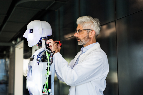 Mature businessman or a scientist with gray hair with a robot.