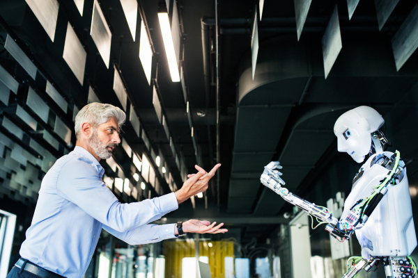 Mature businessman or a scientist with gray hair with a robot.