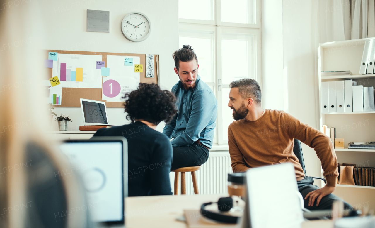 Group of young concentrated male and female businesspeople with laptop working together in a modern office.