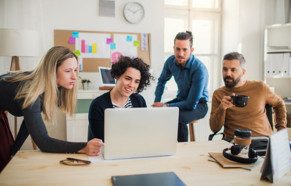 Group of young concentrated male and female businesspeople with laptop having meeting in a modern office.