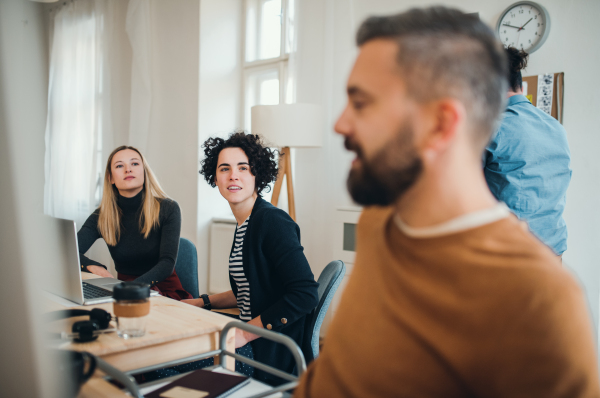 Group of young concentrated male and female businesspeople with laptop working together in a modern office.