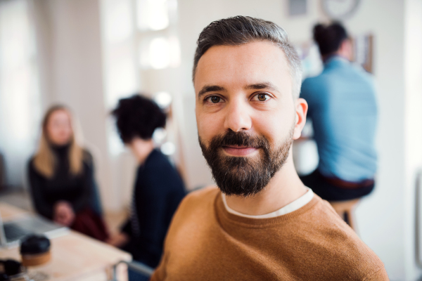 A portrait of young hipster businessman with colleagues in a modern office.