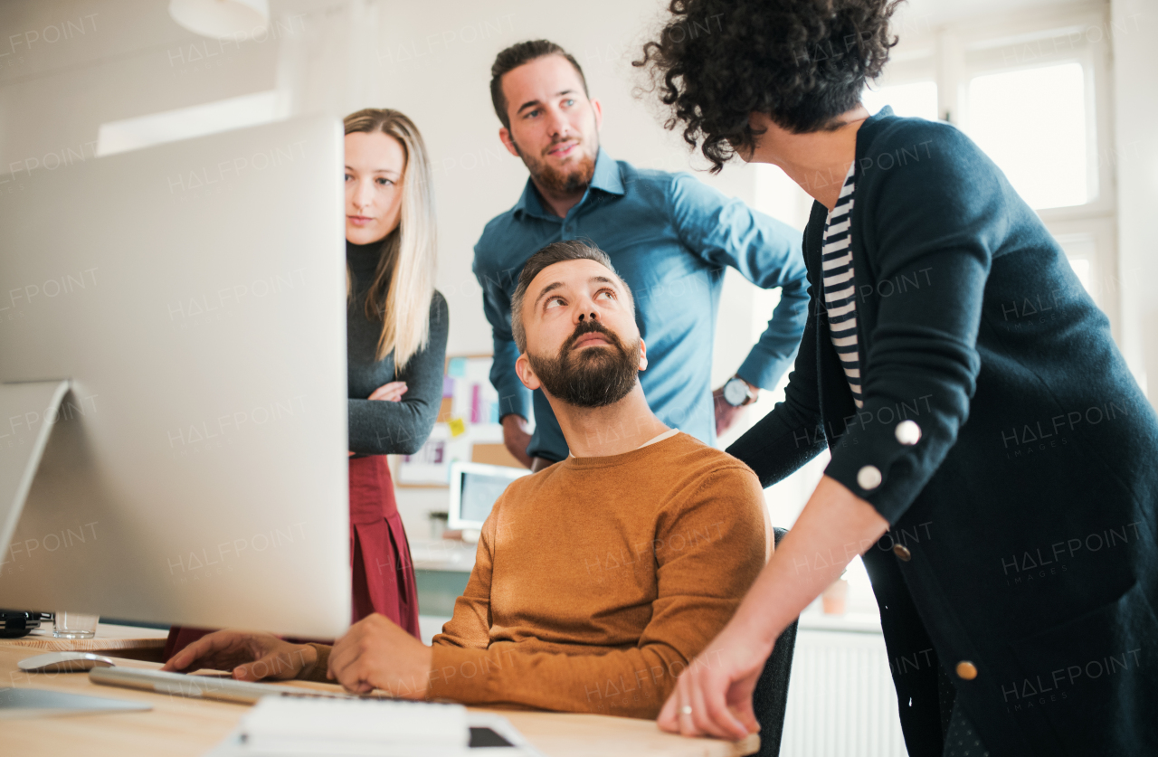 Group of young concentrated male and female businesspeople with laptop having meeting in a modern office.