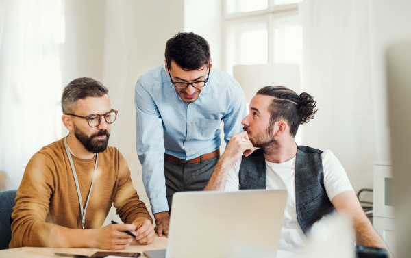 Group of young concentrated male and female businesspeople with laptop working together in a modern office.