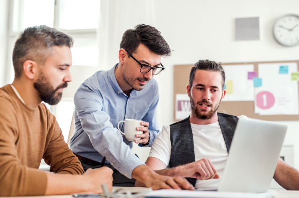 Group of young cheerful businessmen with laptop working in a modern office.