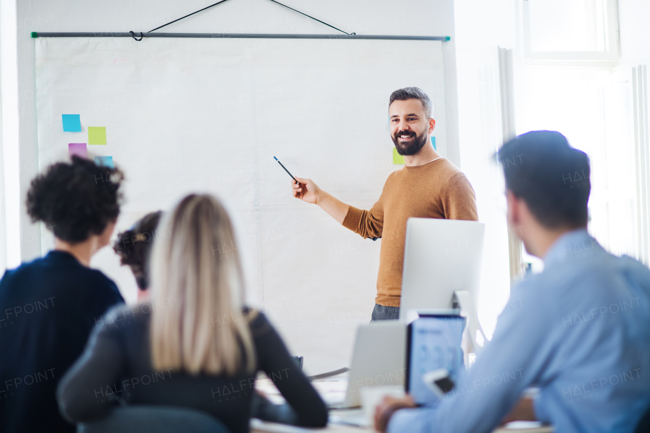 A businessman giving a presentation to colleagues in a modern office. Copy space.