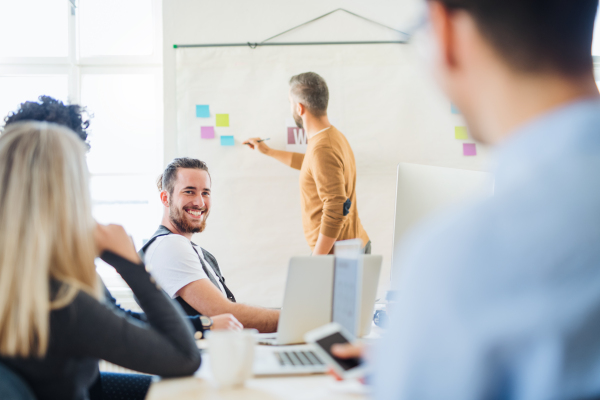 A businessman giving a presentation to colleagues in a modern office. Copy space.