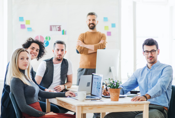 Group of young, cheerful, male and female businesspeople with laptop working together in a modern office.