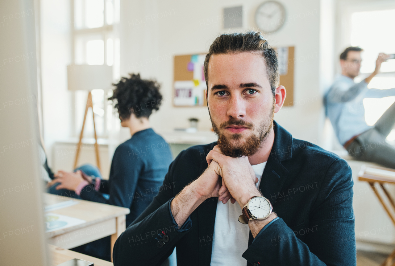 A portrait of young hipster businessman with colleagues in a modern office.