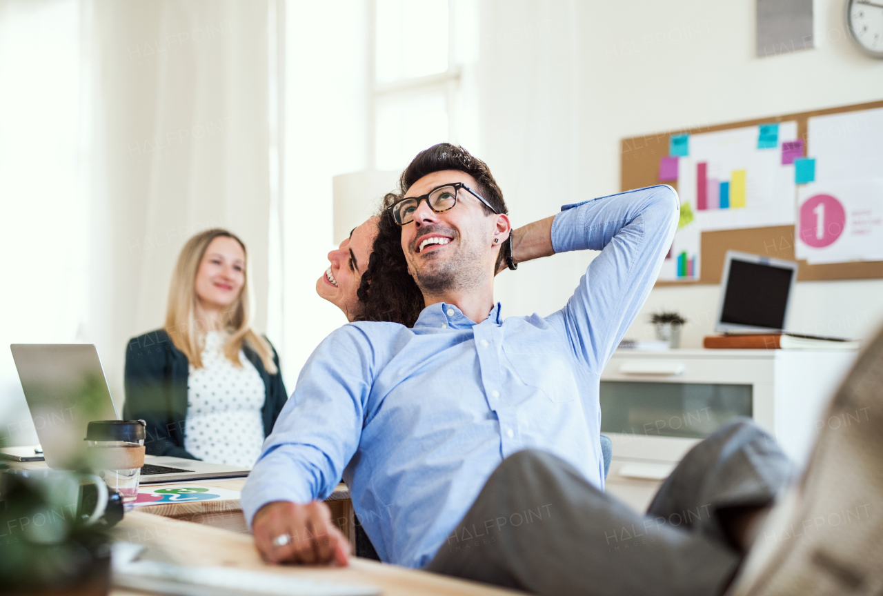 Group of young, cheerful, male and female businesspeople working together in a modern office.