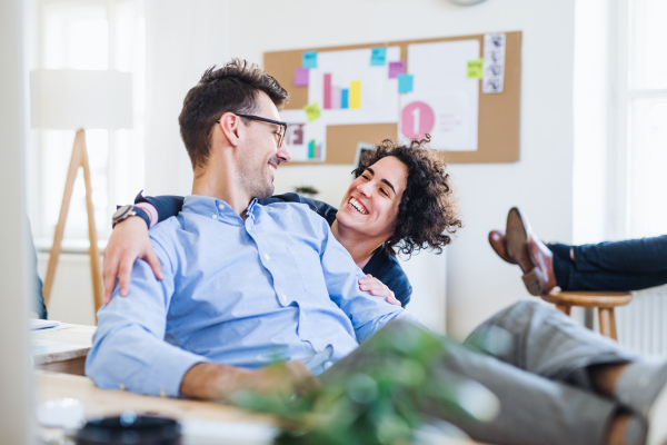 Two young cheerful businesspeople relaxing in a modern office, laughing.