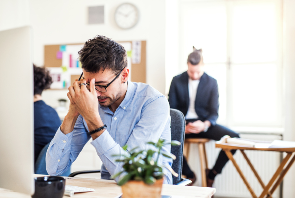 Young frustrated businessman with smartphone working in a modern office, making a phone call.