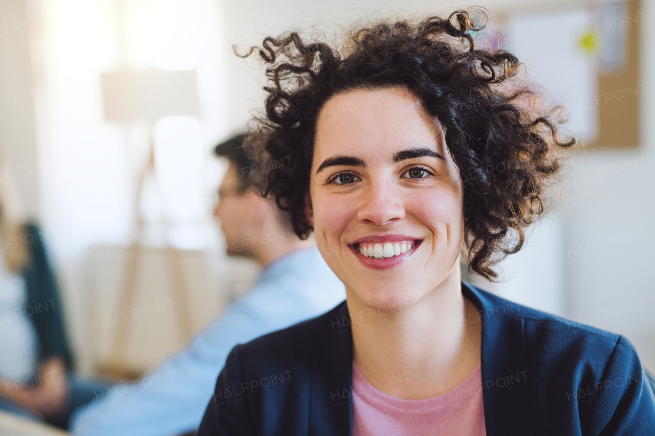 A portrait of young hipster businesswoman with colleagues in the background a modern office.