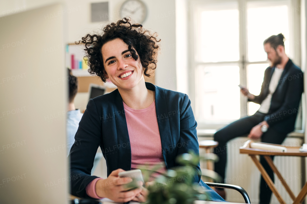 A portrait of young businesswoman with colleagues in a modern office.