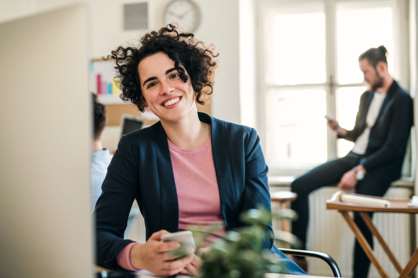 A portrait of young businesswoman with colleagues in a modern office.