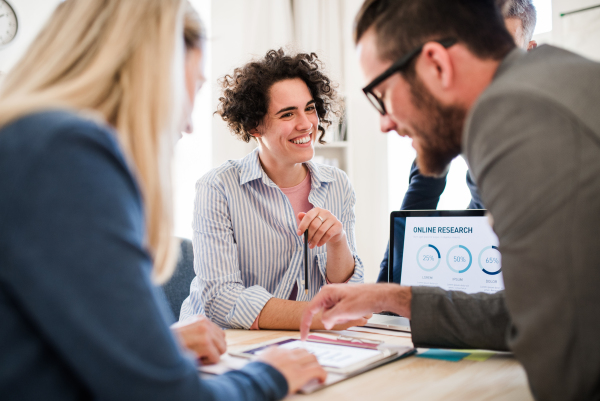 Group of young, cheerful, male and female businesspeople with laptop working together in a modern office.