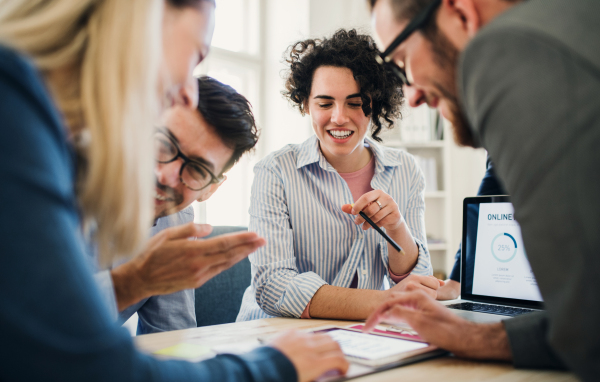 Group of young concentrated male and female businesspeople with laptop working together in a modern office.