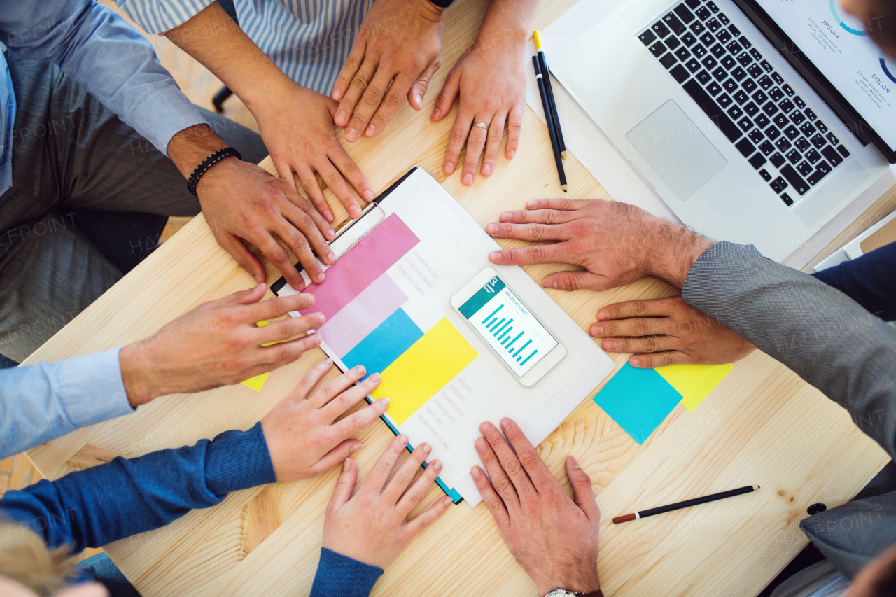 A top view of group of businesspeople with smartphone working together in office, a midsection.