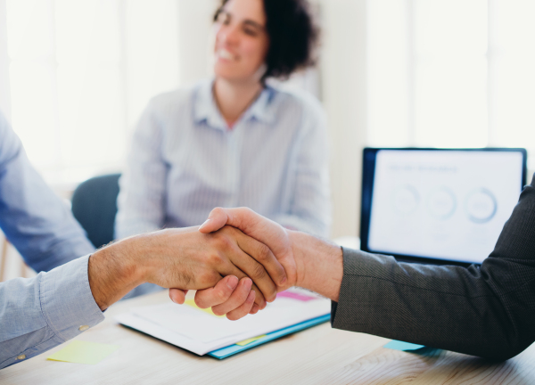 A handshake of male businesspeople in an office. Midsection. Close-up.