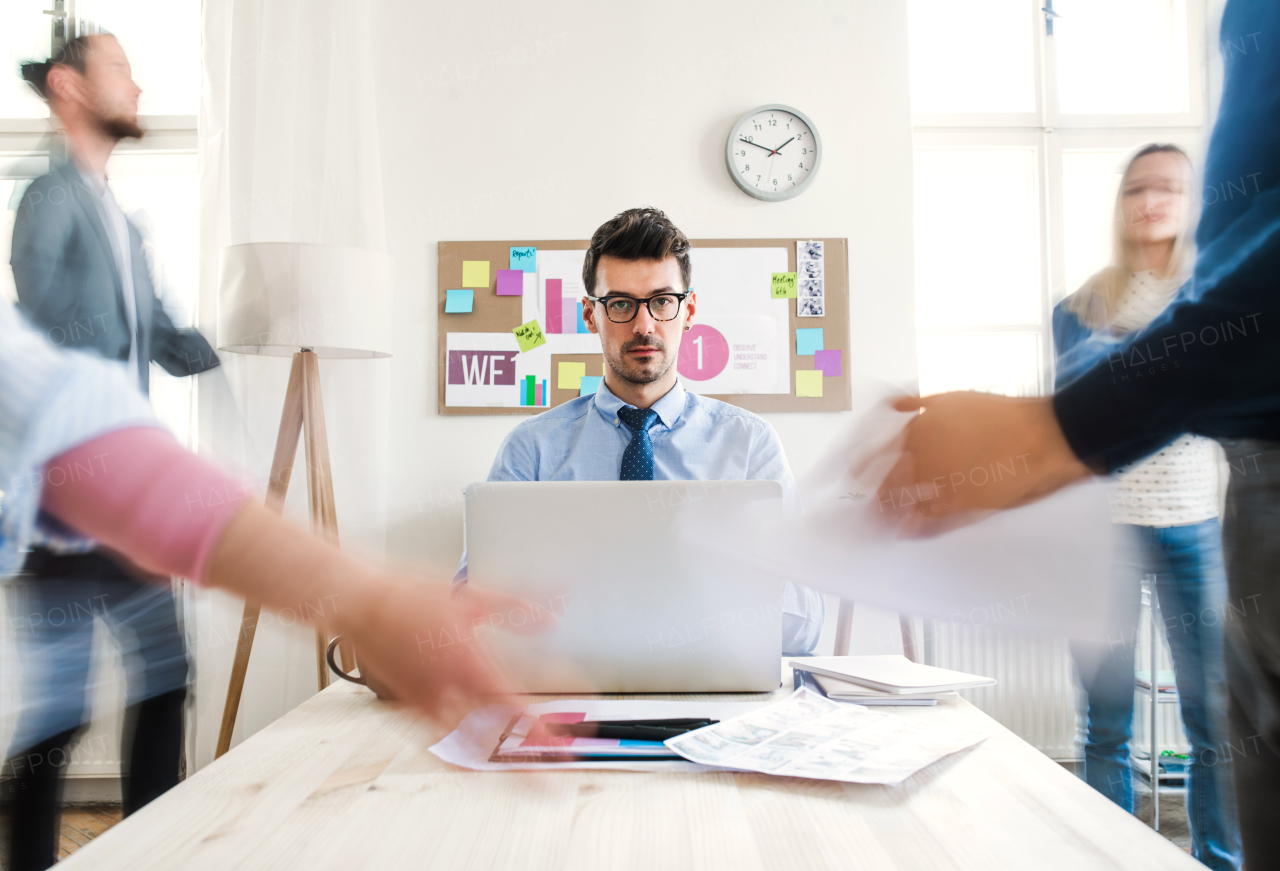 Group of young businesspeople around table in a modern office, having meeting. Motion blur.