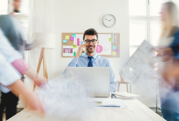 Group of young businesspeople with smartphone sitting around table in a modern office, having meeting. Motion blur.