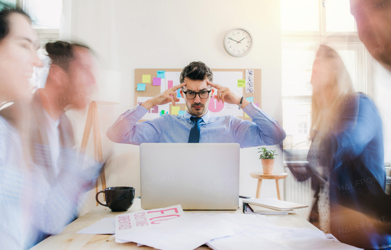 Group of young businesspeople sitting around table in a modern office, having meeting. Motion blur.