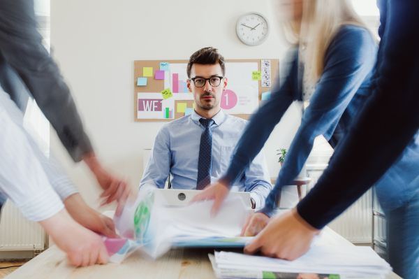 Group of young businesspeople around table in a modern office, having meeting. Motion blur.