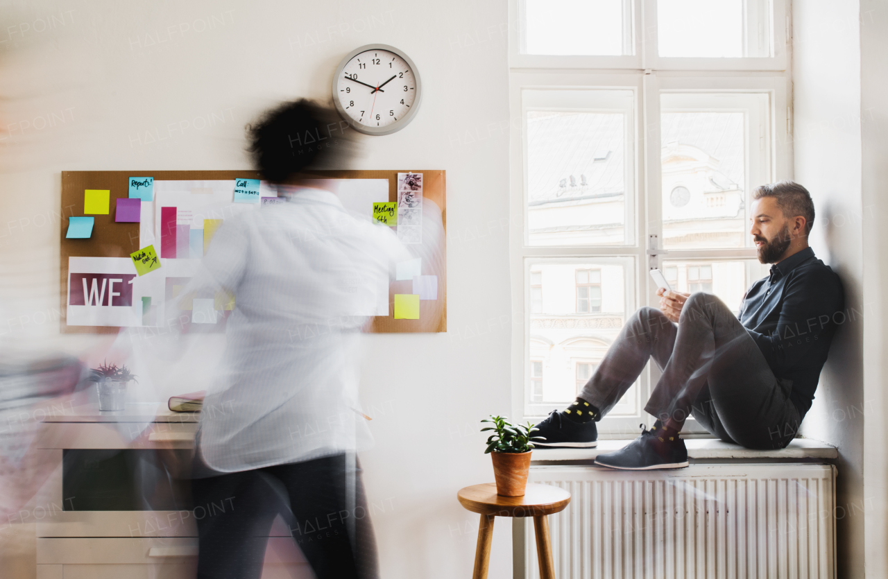 Two young businesspeople in a modern office, having break. Motion blur.