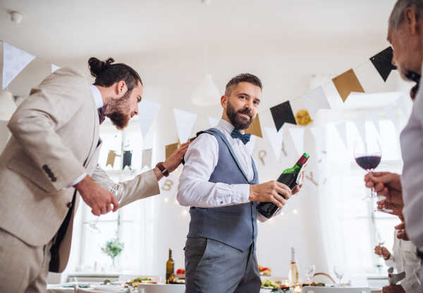 A man pouring happy guests wine on a indoor family birthday party.