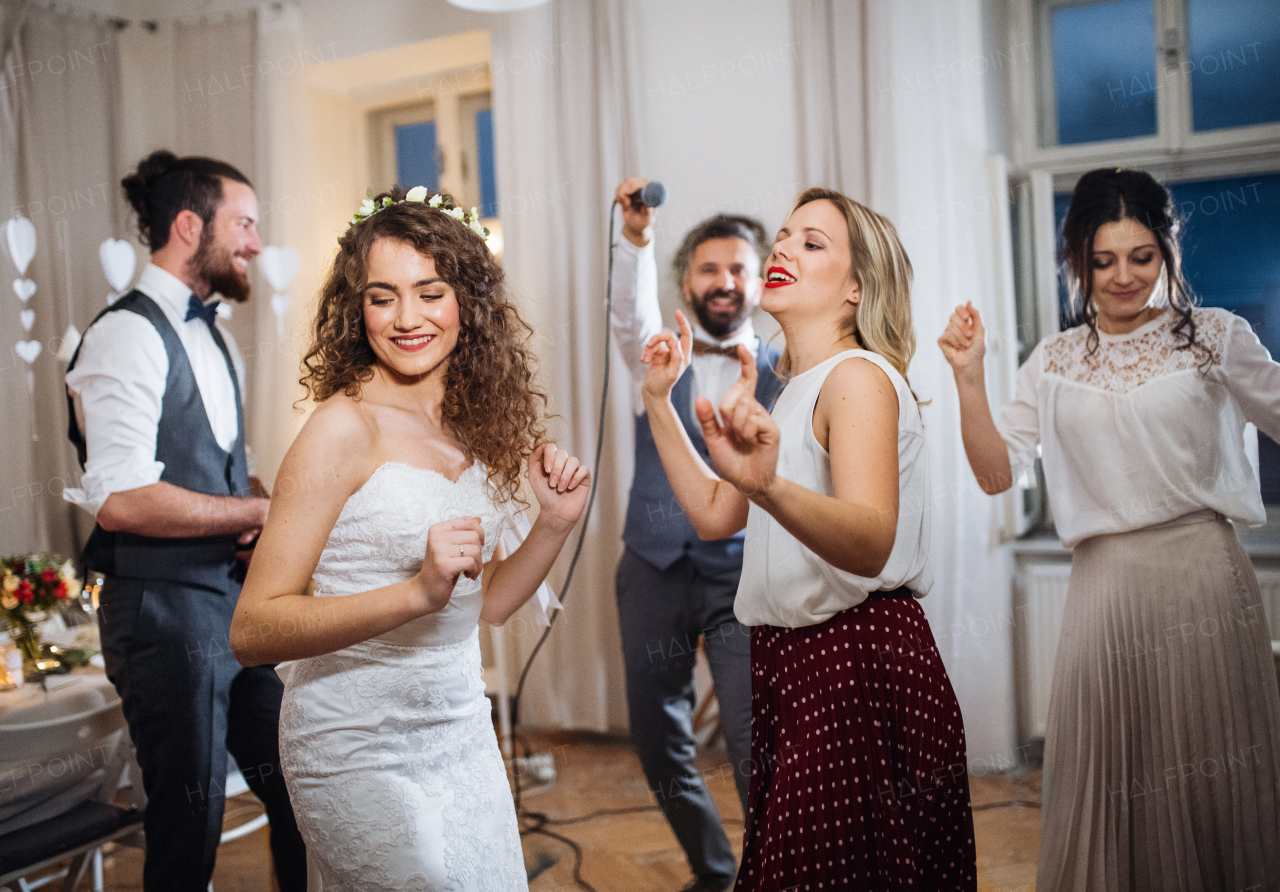 A young cheerful bride with other guests dancing on a wedding reception.