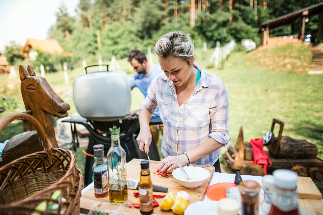 A couple preparing food on a barbecue grill in the backyard. A garden party.