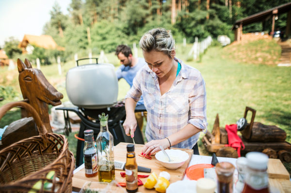 A couple preparing food on a barbecue grill in the backyard. A garden party.