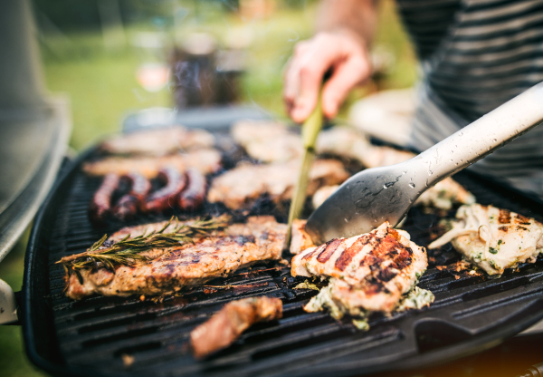 Unrecognizable man cooking seafood on a barbecue grill in the backyard on a sunny day. Close up.