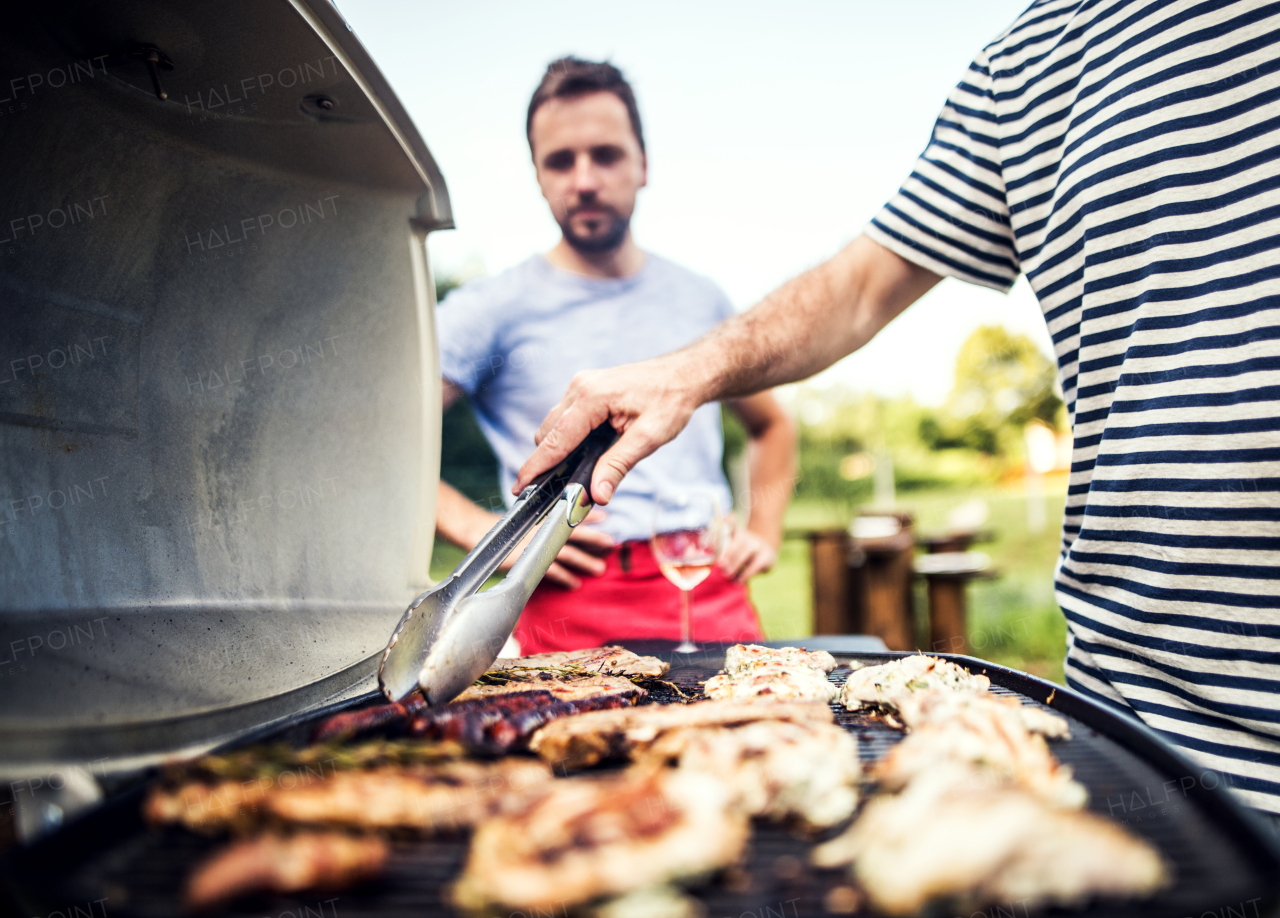 Unrecognizable man cooking seafood on a barbecue grill in the backyard on a sunny day. Close up.