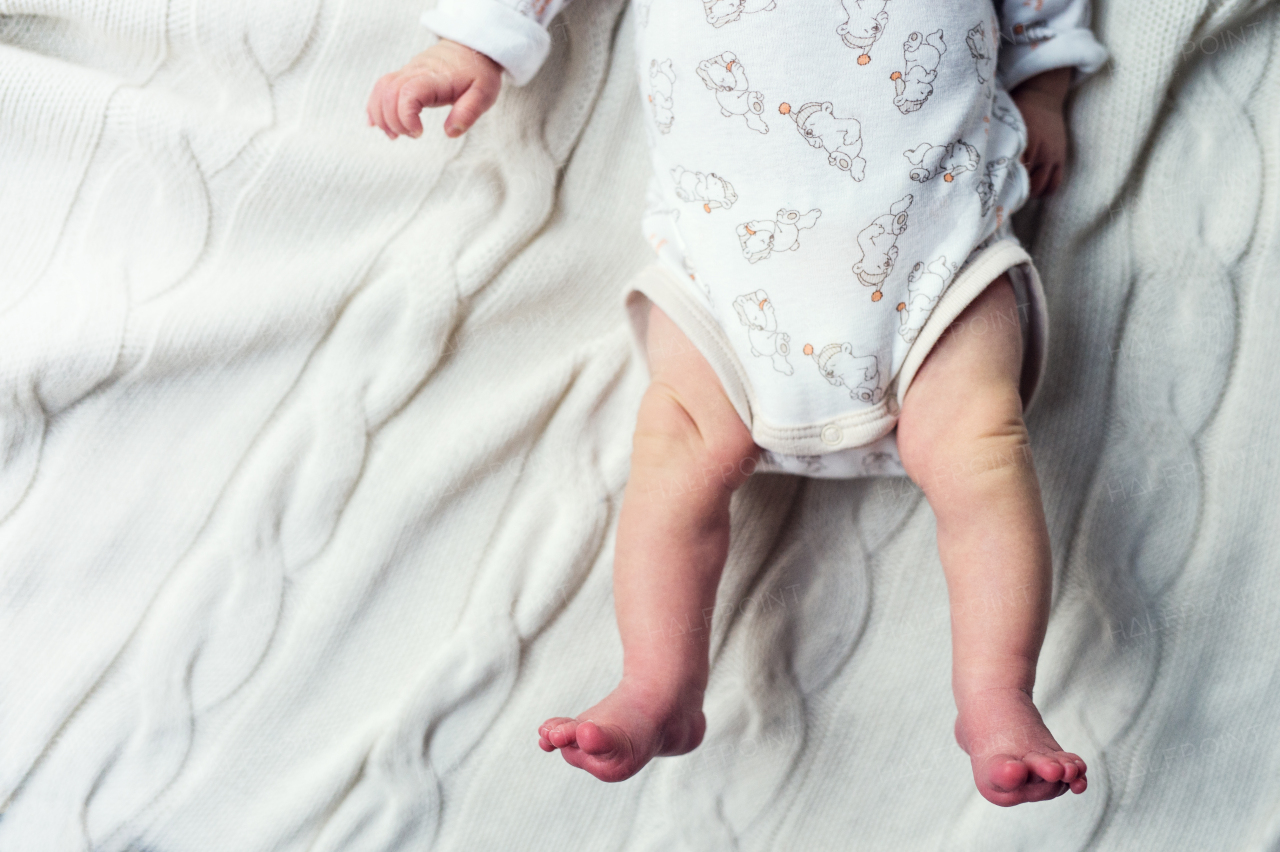 Feet of unrecognizable newborn baby lying on bed. Top view. Copy space.