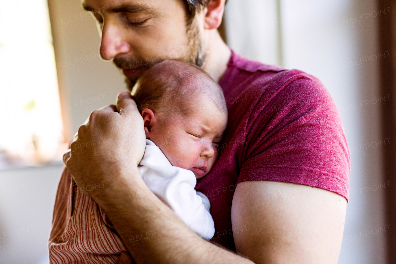 Young father at home holding his cute newborn baby girl.