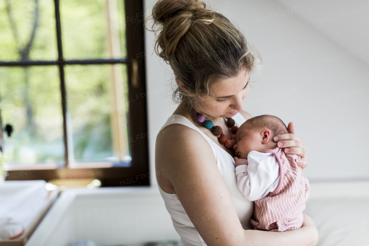 Beautiful young mother at home holding her cute newborn baby girl.