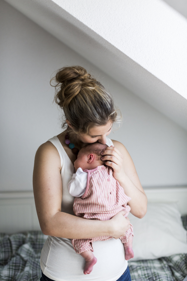 Beautiful young mother at home holding her cute newborn baby girl.