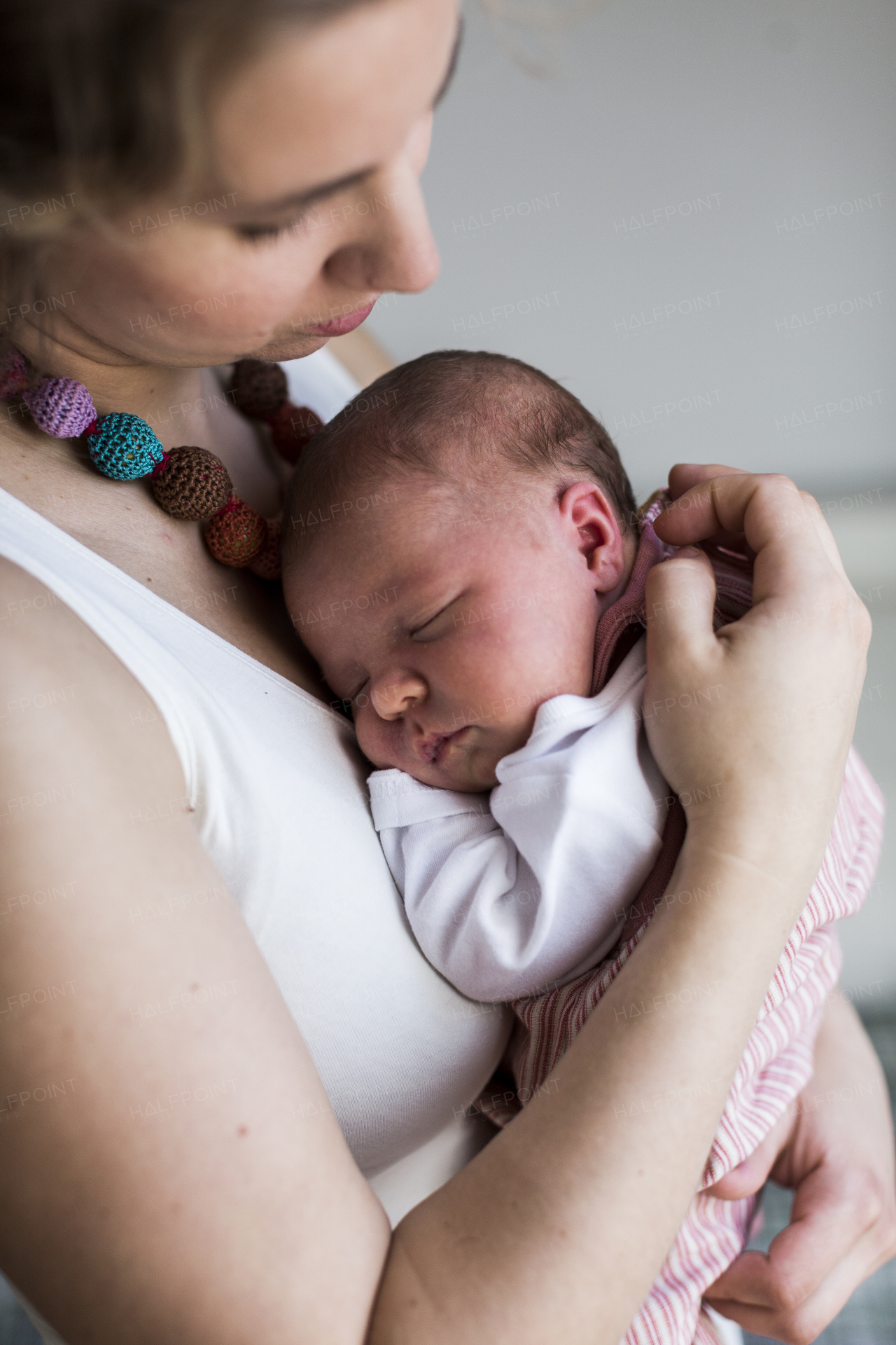 Beautiful young mother at home holding her cute newborn baby girl.