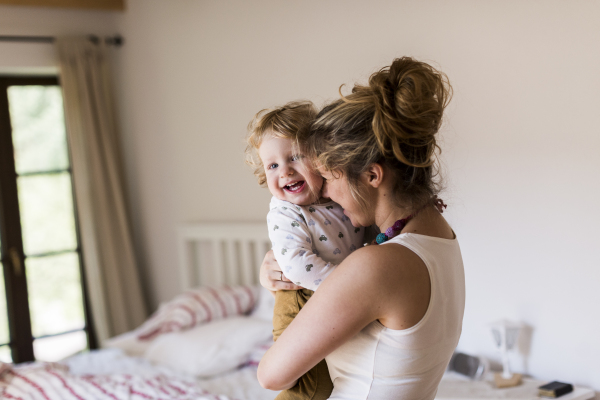 Beautiful young mother at home holding her cute little son in the arms.