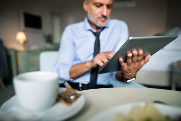 Mature, handsome businessman working on a tablet in a hotel room.