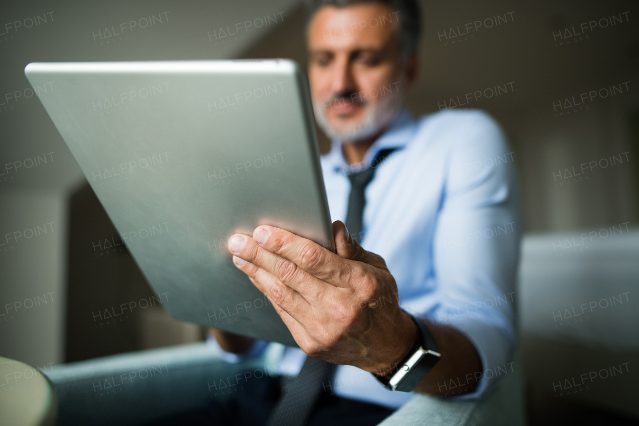 Mature, handsome businessman working on a tablet in a hotel room.