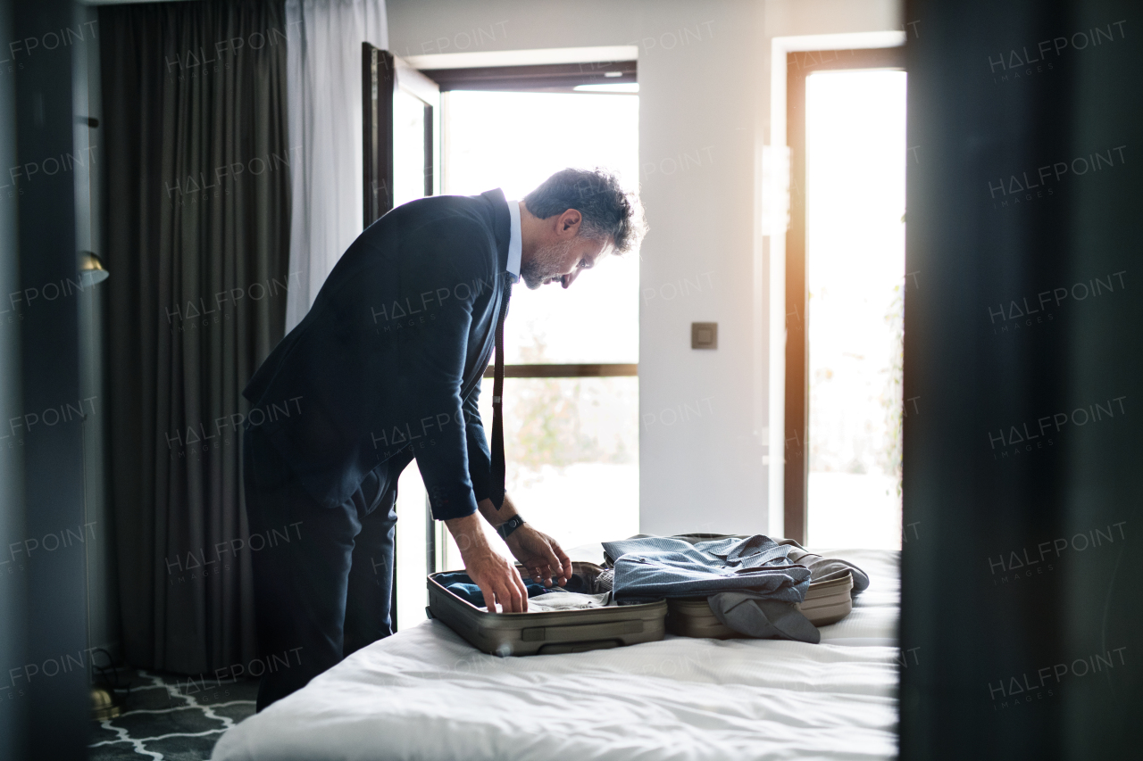 Handsome mature businessman taking his jacket off in a hotel room.