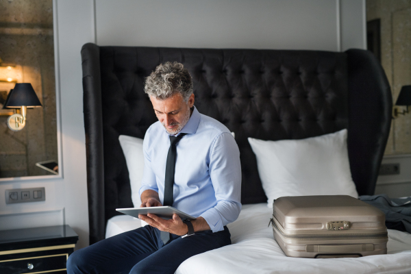 Mature, handsome businessman working on a tablet in a hotel room.