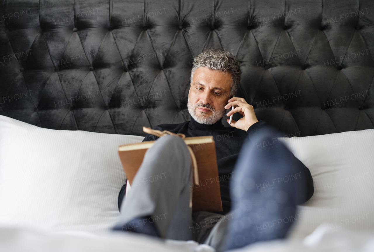 Mature businessman with smartphone in a hotel room. Handsome man making a phone call.