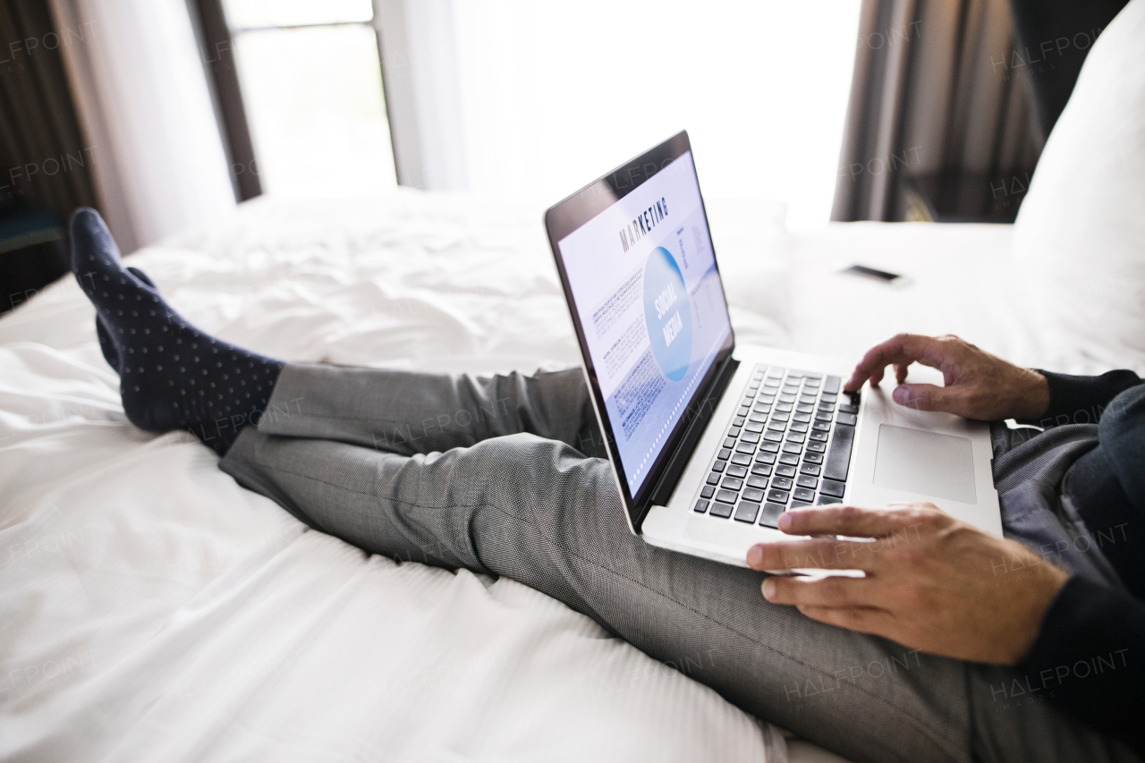 Unrecognizable businessman with laptop in a hotel room. Handsome man working on computer.