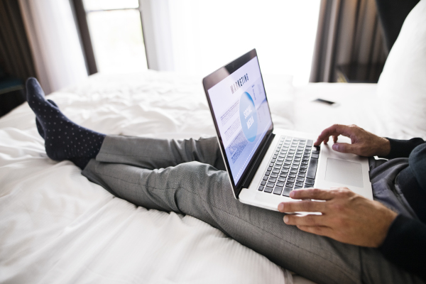 Unrecognizable businessman with laptop in a hotel room. Handsome man working on computer.